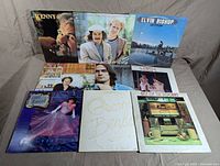 Photo shows the front album covers of 9 records including Kenny Rogers, Simon and Garfunkel, Elvin Bishop, Art Garfunkel, James Taylor, Prism, Linda Ronstadt, George Benson, and The Best of the Doobies.
