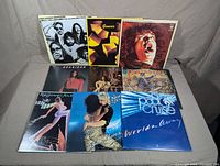 Front view of 9 vinyl records by classic rock and pop artists displayed in three rows.