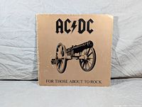 Front cover of AC/DC album For Those About to Rock with cannon image and band logo.