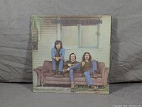 Front cover of Crosby, Stills & Nash self-titled 1969 LP album showing the three band members sitting on a couch outside a house