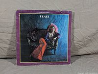 Front cover of Janis Joplin's 1971 Pearl LP record showing Janis seated on a couch with purple border.
