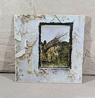 Front cover of Led Zeppelin IV album showing characteristic peeling and worn edges with iconic image of man carrying sticks.