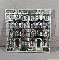 Front cover of Led Zeppelin Physical Graffiti album with detailed artwork showing building facade and visible wear on edges and corners.