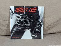 Front cover of Motley Crue LP 'Too Fast for Love' showing leather and studded accessories.