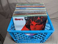 Blue milk crate filled with vinyl records, The Doors album at front
