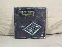 Front cover of Supertramp Crime of the Century LP album showing artwork with hands behind bars on starry black background.