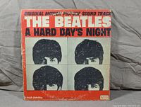 Front cover of The Beatles A Hard Day's Night LP with original red and white design and portraits of band members. Shows wear and creases along edges and corners.
