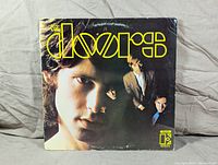 Front cover of The Doors 1967 self-titled album showing band member Jim Morrison's face prominently with yellow 'The Doors' logo.