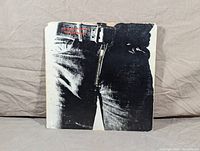 Front cover of The Rolling Stones Sticky Fingers album showing close-up black and white photo of jeans front