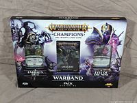 Front image of the Warhammer Age of Sigmar Champions Warband Pack Series 02 box set showing Zarbag's Gitz and Eyes of the Nine packs along with a Savagery booster pack in the center.
