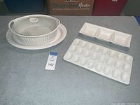 White ceramic server with lid on oval platter, egg tray, and divided dish on table