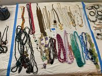Full assortment of necklaces laid out on white sheet showing bead and chain styles