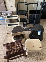 Photo showing entire lot of foot stools and rolling dolly grouped on garage floor.