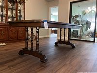 Side view of the double pedestal dining table showing turned wood legs and curved bases.