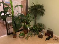 Wide view of faux plants, trees and decorative animal figures arranged on floor corner with reflective background and wooden floor nearby.