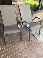 Two matching patio chairs viewed from an angle showing seating and armrests.