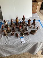 Photo showing large assortment of 23 vintage Tom Clark collectible gnome figurines in different sizes and poses arranged on a gray cloth
