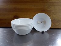 Six white porcelain bowls stacked with one bowl facing upward labeled '5'. Photo shows the plain, unadorned design and dimensions.