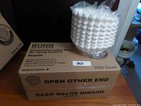 Full box of Bunn commercial coffee filters and a part box with coffee filters stacked in plastic wrap on top of the box