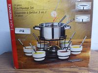 Photo of box showing the 24-piece 3-in-1 fondue set including pot, stand, burner, gel pack holder, 6 white ceramic bowls, fondue forks, and chopsticks.