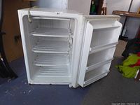 Fridge door open showing three wire racks inside and door shelves for storage.