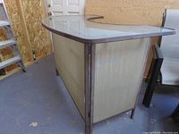 Angled front-left view of the foldable metal and glass bar with brass mesh panels and curved glass top.