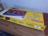 Image of Newon OPEN sign box showing product features like super bright, shatterproof, energy efficient, flashing and scrolling lights.