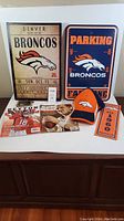 Photo of all Denver Broncos fan lot items arranged on a table including signs, hat, magazines and ornament.