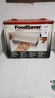 Boxed FoodSaver Compact II vacuum sealer showing front and product image on box.
