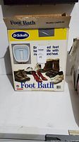 Original box for Dr. Scholl's Foot Bath Massager model CNFRT-50 with promotional text and images.