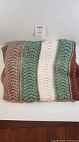 Front view of the folded hand knitted blanket showing striped colorful wave pattern and texture.