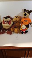 Photo showing all four stuffed toys in the lot together on a white surface, including Taz, Alf, Garfield, and Yogi Bear characters.
