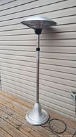 Full view of the 6 ft outdoor electric heater standing on wooden deck against siding.