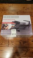 Sealed retail box front showing Black+Decker Belgian waffle maker branding and product image.