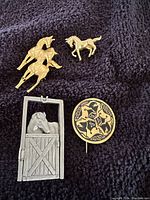 Four horse-themed brooches laid on fabric, showing size and details