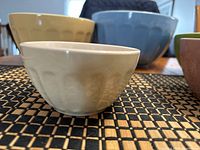 Close-up of five mixing bowls in various colors showing textured exteriors and marks from stacking.
