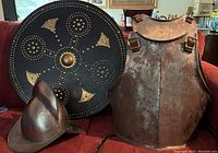 Shield leaning against breastplate with helmet in front