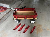 Complete wagon with red removable sides and four white and black wheels, with ski attachments laid out in front.