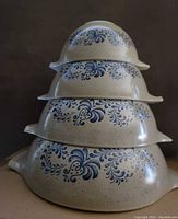 Four PYREX Homestead Cinderella mixing bowls stacked largest to smallest showing side pouring spouts and blue floral patterns