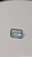 Natural sky blue aquamarine gemstone with octagon cut displayed against plain background, showing facets and clarity.