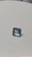 Close-up image of a natural sky blue aquamarine octagon cut gemstone showing facets and clarity on a white background.