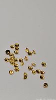 Photo showing scattered small bright yellow diamond-cut sapphires approximately 1.5-1.9mm in size.