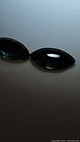 Two marquis cut sapphires in blue, teal, and green hues, showing their shape and color.