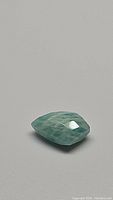 Image showing a single 1.52ct natural amazonite gemstone cut in a fancy kite shape with checkerboard facets, greenish-blue color with natural patterns visible.