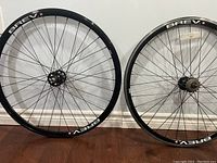 Front and rear Brev bicycle wheels side by side on the floor showing the wheel rims with Brev branding