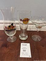 Three Hard Rock glasses displayed on floor including hurricane style and others with logos.