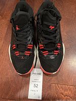 Front view of pair of black Air Jordan 29 basketball shoes with red accents and white midsoles on wooden floor.