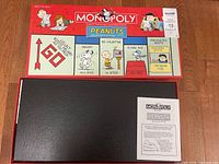Box top showing Monopoly Peanuts Collector's Edition artwork and branding with character illustrations and game instructions booklet on top.