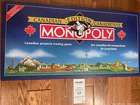 Closed Monopoly Canadian Edition game box, bilingual English and French, showing Canadian landmarks and maple leaf logos on blue background.