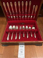 Full view of 33 piece silverware set in wooden box with red velvet lining, showing knives, forks, and spoons.